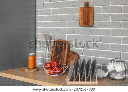 Wooden countertop with apples, plate rack and bottles of juice in modern kitchen Royalty-Free Stock Photo #2373567989