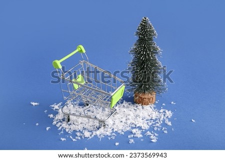 Shopping cart with Christmas tree and snow on blue background