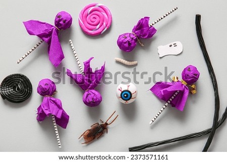 Sweet lollipops with liquorice, jelly eye and cockroach for Halloween party on grey background