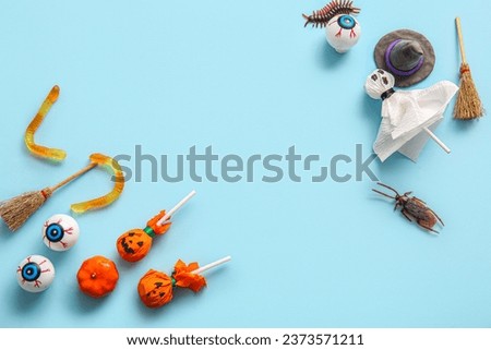 Sweet lollipops with candy bugs, jelly worms and eyes for Halloween party on blue background