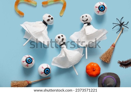 Sweet lollipops with jelly worms and eyes for Halloween party on blue background
