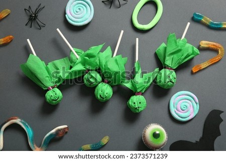 Sweet lollipops for Halloween party with jelly worms and eye on black background
