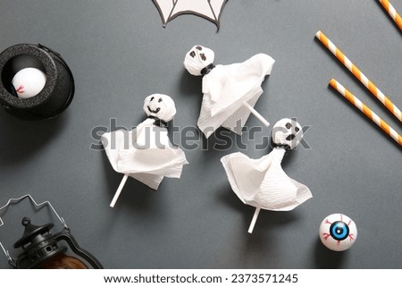 Sweet lollipops with jelly eyes and straws for Halloween party on black background