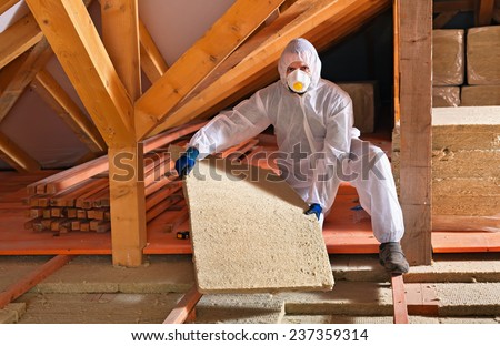 Man laying thermal insulation layer under the roof - using mineral wool panels