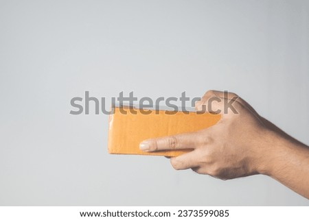 "The man is holding a package against a clean, pristine white background, creating a striking contrast."