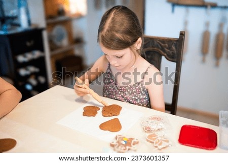 Culinary workshops for children and gingerbread decorating. Young girl decorating gingerbread cookies in the shape of a heart, a fox and a cupcake Royalty-Free Stock Photo #2373601357