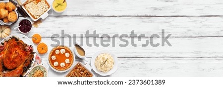 Traditional Thanksgiving turkey dinner. Top down view corner border on a rustic white wood banner background. Turkey, mashed potatoes, stuffing, pumpkin pie and sides.