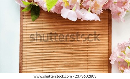 Branch with pink cherry blossom flowers on white background and bamboo napkin or mat. Texture, frame, copy space, background
