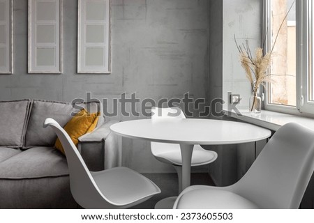 Apartment with white chairs and round wooden, white table.