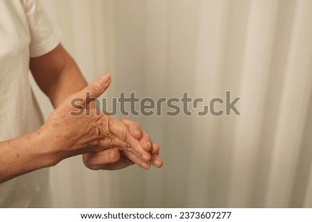 A woman uses her hand to hold the palm of her other hand to feel pain, pain, and tingling, combiningsymptoms of Guillain barre and numbness of the hand. Elderly woman tries to massage herself to relie