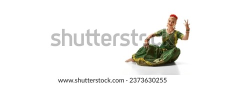 Stylish, beautiful woman in traditional indian costume dancing against white studio background. Concept of beauty, fashion, India, traditions, lifestyle, choreography, art. Copy space for ad. Banner