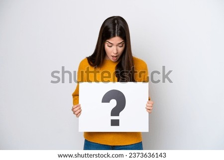 Young Brazilian woman isolated on white background holding a placard with question mark symbol