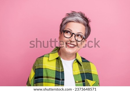 Photo of good mood retired woman with short hairstyle wear checkered shirt look at offer empty space isolated on pink color background