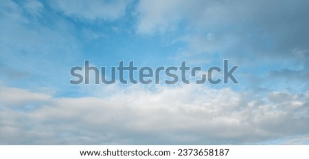 A serene blue sky adorned with fluffy white cumulus and stratus clouds. This image provides the perfect backdrop for projects seeking to capture the essence of air and atmosphere