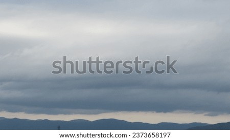 Autumn brings overcast skies adorned with gray stratus clouds, hinting at impending rain. This full-screen view provides ample space for text or design elements, making it perfect for various projects Royalty-Free Stock Photo #2373658197