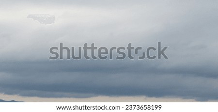 Autumn brings overcast skies adorned with gray stratus clouds, hinting at impending rain. This full-screen view provides ample space for text or design elements, making it perfect for various projects Royalty-Free Stock Photo #2373658199