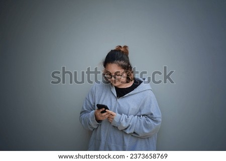 A Girl Leaning Against The Wall While Using Her Phone