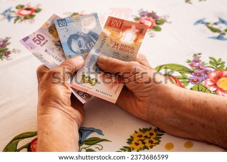 Mexico money, Eldelry woman holds several mexican pesos banknotes in her hand, Financial problems of pensioners, low pensions, high prices Royalty-Free Stock Photo #2373686599