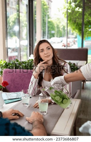 elegant young girl client talking to waiter while looking through menu. bar lifestyle concept.