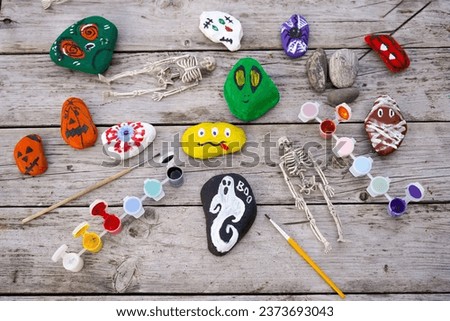 Diy concept. A detailed picture of a child's hands drawing on stones Halloween characters. Art project for children. Party decor.