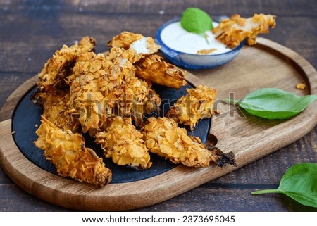 
 Crispy home made  deep fried   chicken strips . Breaded  with cornflakes chicken  breast fillets  with chilly peppers and fresh   basil on wooden rustic background Royalty-Free Stock Photo #2373695045