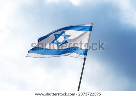 The flag of Israel on a field and a cloudy sky background. Memorial day-Yom Hazikaron, Patriotic holiday Independence day Israel - Yom Ha'atzmaut concept.