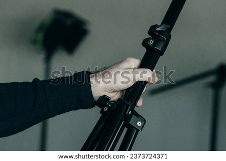 male hand holding tripod on a grey background. High quality photo