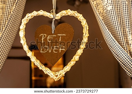 cute wicker heart with a wooden heart inside with a message about love for animals on the window. Caring for Pets