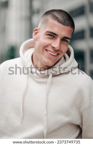 A young Caucasian male model wearing a white hoodie and posing on the street Royalty-Free Stock Photo #2373749735