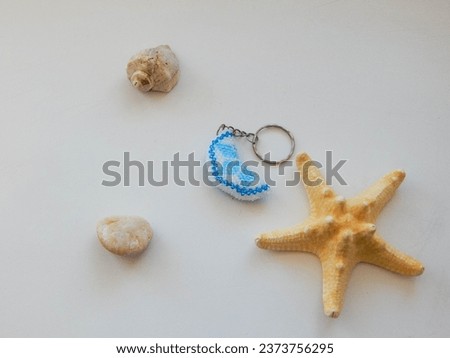 Colored key chain and sea conch. Bead colorful key chain on a white background