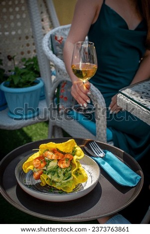 The waiter brings the girl an appetizer of fried shrimp and chips, the girl customer holds a glass of champagne in her hand