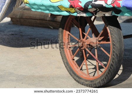 a cutout of a photo of a rusty cart wheel on a cement cast floor