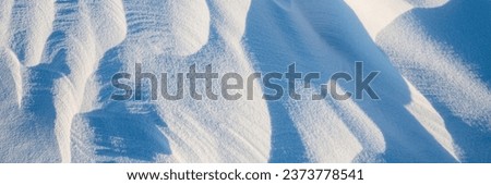 Snow texture. Wind sculpted patterns on snow surface. Wind in the tundra and in the mountains on the surface of the snow sculpts patterns and ridges. Arctic, Polar region. Winter panoramic background.