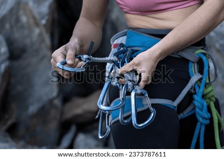 Young woman completing climbing equipment. Midsection of woman with climbing equipment standing on rock