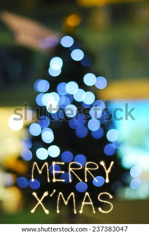 Merry X' Mas sparkle firework writing with defocused light Christmas tree