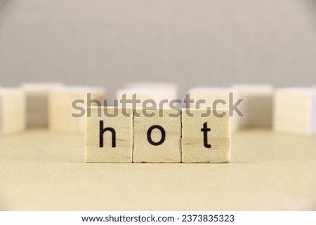 Short word english letter with text "hot" on a small wooden cubes block with bright background.Copy space concept and selection focus.
