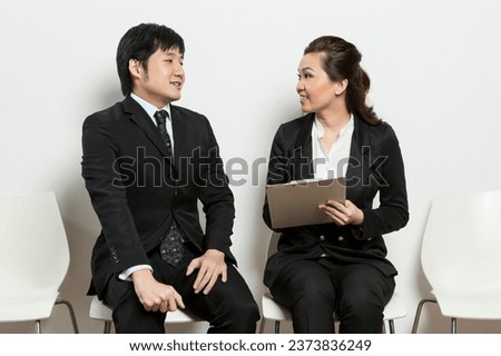 Chinese business woman interviewing an uncomfortable looking male applicant. Royalty-Free Stock Photo #2373836249