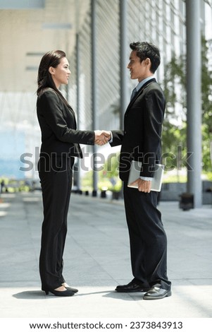 Chinese Businessman and businesswoman shaking hands outside the office Royalty-Free Stock Photo #2373843913