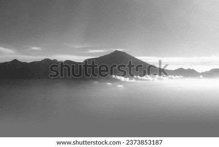 Stunning aerial view of Mount Rinjani in monochrome photo on Lombok Island, Indonesia. Clear skies complemented the majestic mountains, while a light layer of mist blanketed the landscape below.
