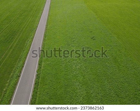 View from above of a straight road between grass fields in the landscape 