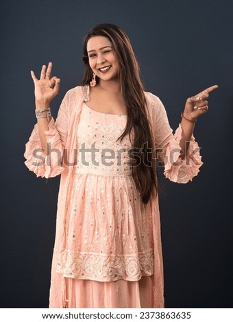 Portrait of a successful cheerful young girl presenting something with a finger with a happy smiling face.