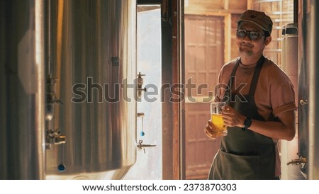 Asian male owner drinking for examining  beer quality at craft brewery factory.
