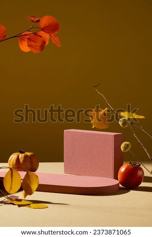 Empty platform for cosmetics presentation. Mockup with red geometries podiums decorated with pumpkin, tomato and dry autumn leaves on brown background
