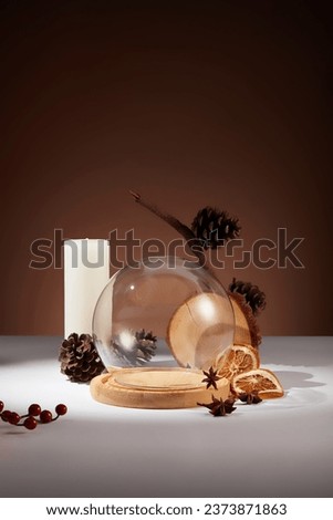 An empty glass cage surrounded by few dried orange slices, star anise and pine cones. Traditional Christmas greetings include Merry Christmas and Happy Christmas