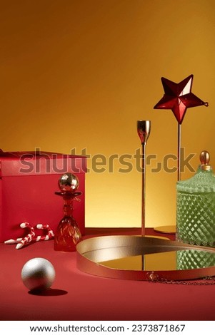 An empty mirror tray decorated with minimal baubles, candy cane and a large gift box. Traditions associated with the Christmas holiday are diverse in their origins and nature