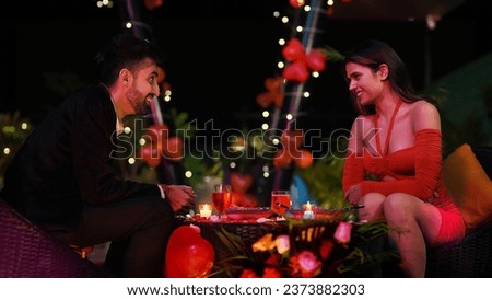 Happy Indian smiling couple sitting on chair talking night dating outdoor home. Beautiful husband wife communicating outside house celebrating anniversary spend time enjoying holiday weekend together Royalty-Free Stock Photo #2373882303