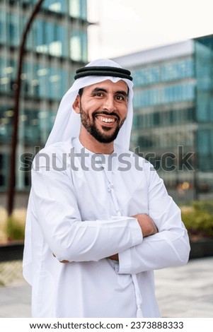 Arab middle-eastern man wearing emirati kandora traditional clothing in the city - Arabian muslim businessman strolling in urban business centre. Royalty-Free Stock Photo #2373888333