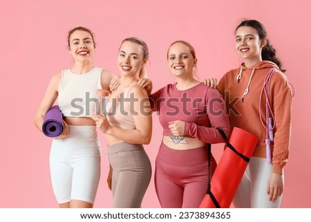 Group of sporty young women with equipment on pink background