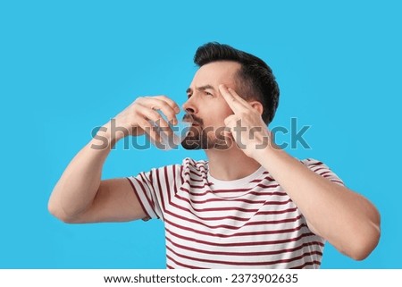 Young man drinking water with dissolved tablet on blue background