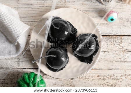 Plate of tasty caramel apples for Halloween, spider web and eye on white wooden background